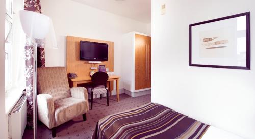 a hotel room with a bed and a desk and a tv at Home Hotel Bilan in Karlstad