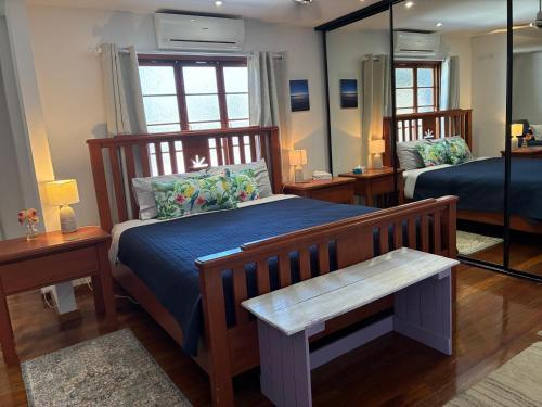 a bedroom with a bed with blue sheets and a mirror at Queenslander leafy Whitfield in Edge Hill
