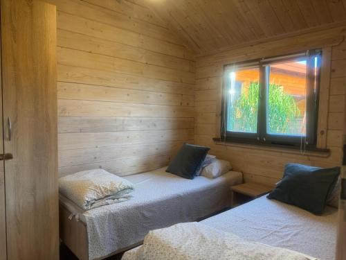 a room with two beds in a wooden cabin at Domki Nad Stawem Mazury D4 in Mrągowo