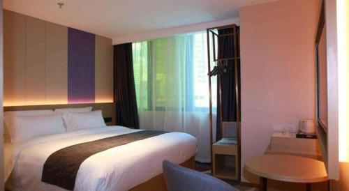 a bedroom with a bed and a table and a window at Lavande Hotel Shenzhen East Gate Wanxiang City Guomao Metro Statipn in Shenzhen