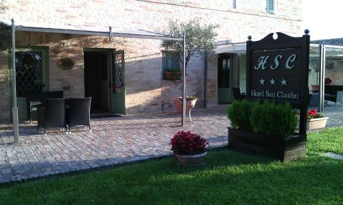 a sign in front of a building with a brick yard at Hotel San Claudio in Corridonia