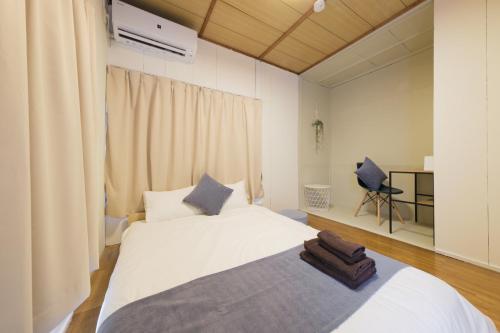 a bedroom with a large white bed and a chair at Neuk Nakanosima in Ikuta