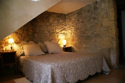 ein Schlafzimmer mit einem Bett mit einer Steinmauer in der Unterkunft Domaine Chanoine Rambert in Saint-André-dʼOlérargues