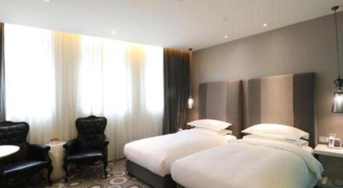 a hotel room with two beds and a chair at Jinjiang Metropolo Hotel Classiq Shanghai Off Bund in Shanghai
