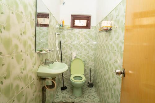 a bathroom with a green toilet and a sink at StayEase in Batticaloa