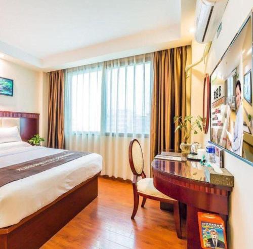a hotel room with a desk and a bed at GreenTree Inn Guangzhou Baiyun International Airport Huaxi Road Express Hotel in Guangzhou