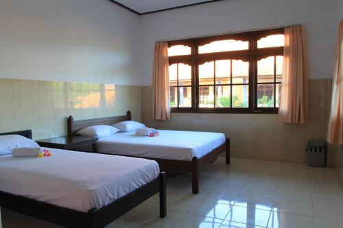 a room with two beds and a window at Losmen Cempaka 3 in Kuta