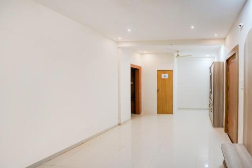 a hallway with white walls and wooden doors at HOTEL O AK Stay Inn in Dhantoli
