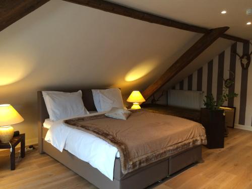 a bedroom with a bed with white sheets and two lamps at Hotel Dufays in Stavelot
