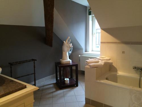 a bathroom with a statue of a hand next to a bath tub at Hotel Dufays in Stavelot