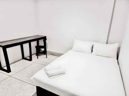 a bedroom with a white bed and a table at XX Mitr Inn Khaosan Road - มิตร อินน์ ถนนข้าวสาร in Bangkok