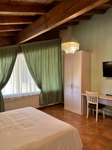 a bedroom with a bed and a desk and a chandelier at Hotel Airone in Piadena