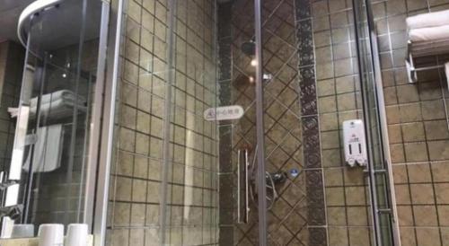 a shower with a glass door in a bathroom at GreenTree Inn Qingdao Jiaozhou Jiaoping Road Express Hotel in Qingdao