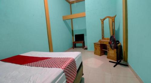 a bedroom with a bed and a dresser and a mirror at Hotel O Rania Kost Simpang Rimbo in Jambi