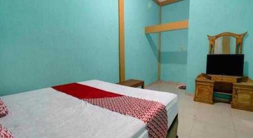 a bedroom with a bed and a tv in it at Hotel O Rania Kost Simpang Rimbo in Jambi