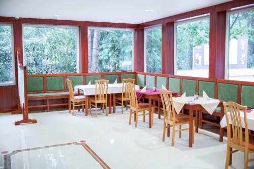 a dining room with tables and chairs and windows at Wellness Hotel Szindbád in Balatonszemes