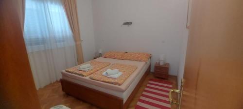 a small bedroom with a bed with two pillows on it at Kopara apartmanok in Rogoznica