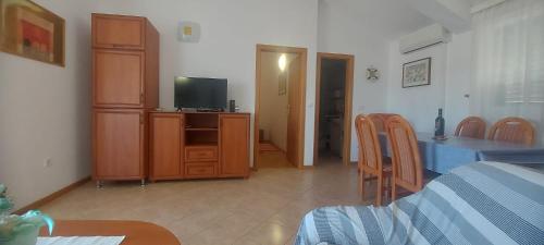 a living room with a television and a table and chairs at Kopara apartmanok in Rogoznica