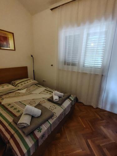 a bedroom with a bed with towels and a window at Kopara apartmanok in Rogoznica