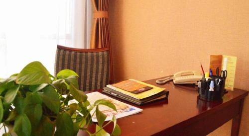 a desk with a plant and a phone and a book at Datong Tiangui International Hotel in Datong