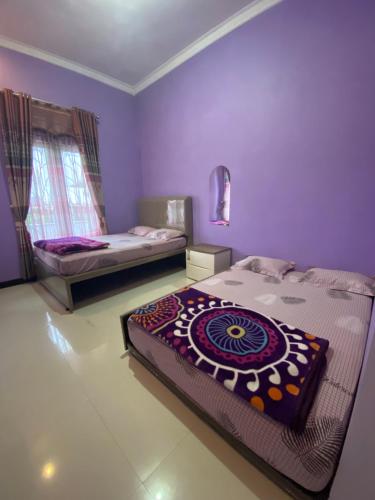 two beds in a room with purple walls at Homestay Dieng Mahameru in Kejajar