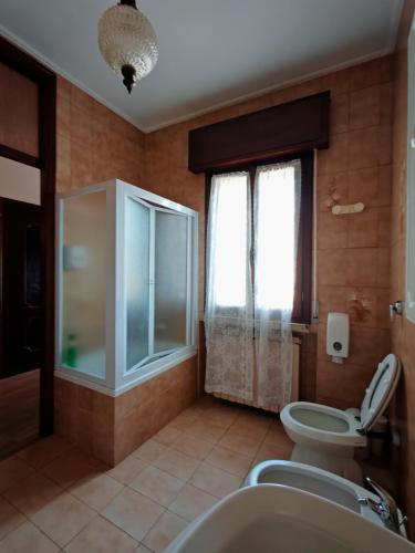 a bathroom with a toilet and a sink and a window at Bocasa affittacamere in Casaleone