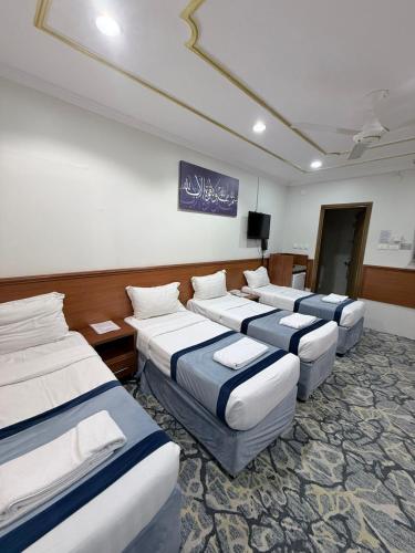 a room with four beds and a flat screen tv at Elaf Al bait ايلاف البيت in Mecca