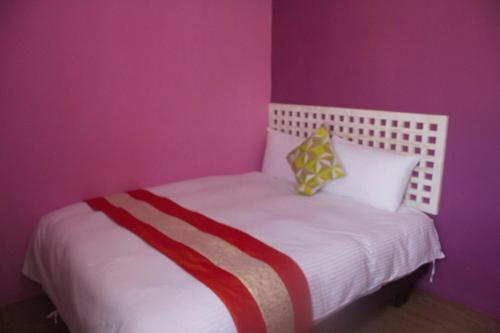 a bedroom with a white bed with purple walls at 文風小築Wen-Feng House-免費停車 in Kenting