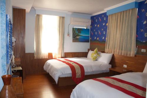 a hotel room with two beds and a window at 文風小築Wen-Feng House-免費停車 in Kenting