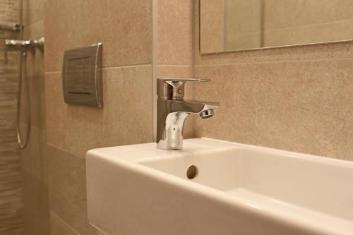 lavabo con grifo y espejo en Erhardt Superior Rooms, en Sopron