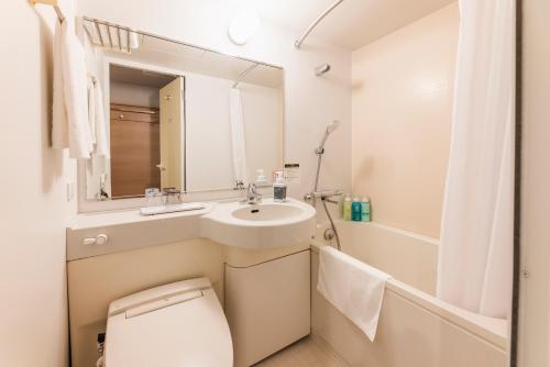 a bathroom with a sink and a toilet and a mirror at Sotetsu Fresa Inn Yokohama Sakuragi-cho - Renovated in June 20th 2025 in Yokohama