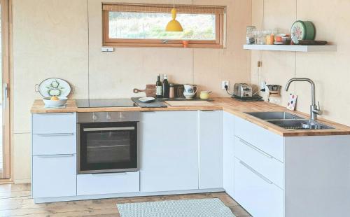 a kitchen with white cabinets and a sink at Self-Built Cabin With Views Over Leirvik in Bø
