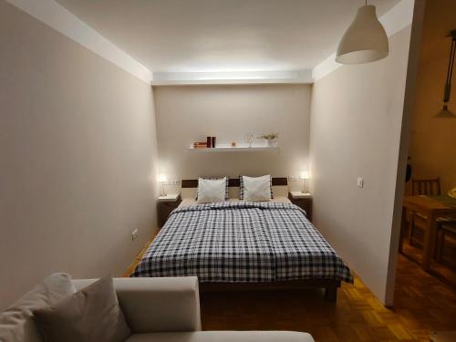 a bedroom with a bed and a couch at Grünerbalkon Ferienappartement in Klagenfurt