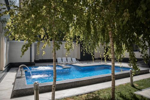 a swimming pool with chairs and trees in a yard at Turon Lux Hotel in Samarkand