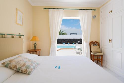 een slaapkamer met een bed en uitzicht op een zwembad bij Villa Pippa in Puerto del Carmen