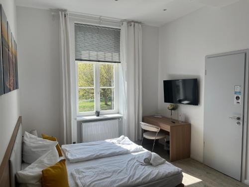 プットブスにあるBed & Breakfast am Schlossparkのベッドと机と窓のある寝室