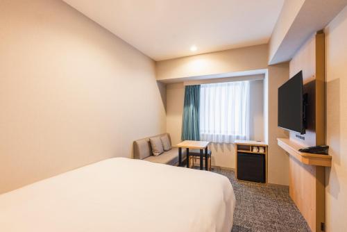 a hotel room with a bed and a television at Sotetsu Fresa Inn Yokohama Sakuragi-cho - Renovated in June 20th 2025 in Yokohama