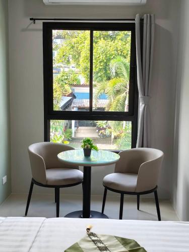 a table and two chairs in a room with a window at Le Wadee Residence in Bang Tao Beach