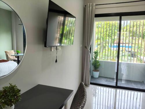 a mirror in a room with a bed and a window at Le Wadee Residence in Bang Tao Beach