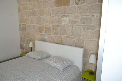 a bed with two pillows in front of a stone wall at Apartments Martinis in Vis