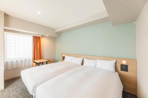 a large white bed in a room with a window at Sotetsu Fresa Inn Yokohama Sakuragi-cho - Renovated in June 20th 2025 in Yokohama