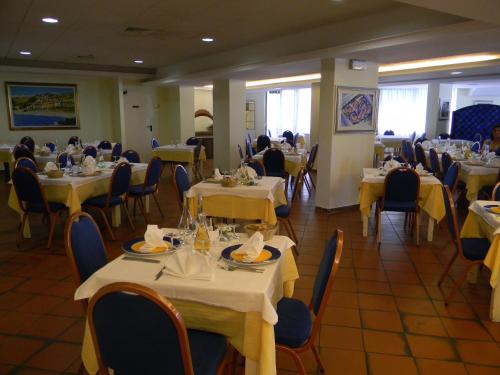 een restaurant met tafels en stoelen en mensen die er zitten bij Hotel Talao in Scalea