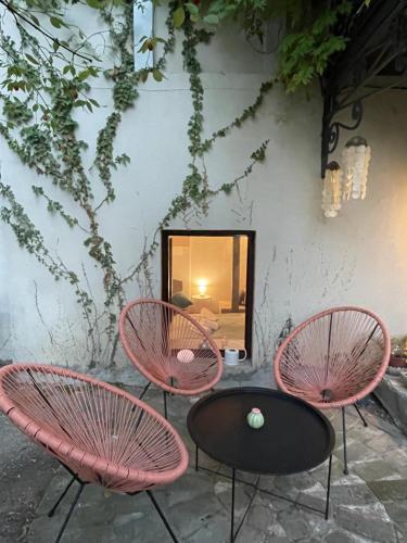 three pink chairs and a table in front of a wall at Terracotta in Tʼelavi