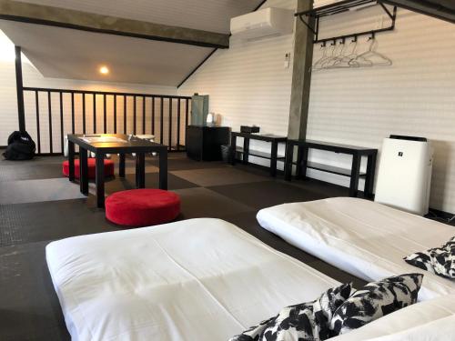 a room with two beds and a table in it at Hostel SAMURISE 81INN in Fujikawaguchiko