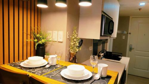 a table with plates and glasses on it in a kitchen at Modern Elegance Escape in Azure North Bali Tower near Malls, Airport and NLEX in San Fernando