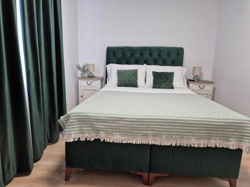 a bedroom with a large bed with a green headboard at D&D Central Apartment in Tulcea