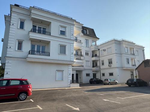 a large white building with cars parked in a parking lot at Apartment Aqua Serena in Palić