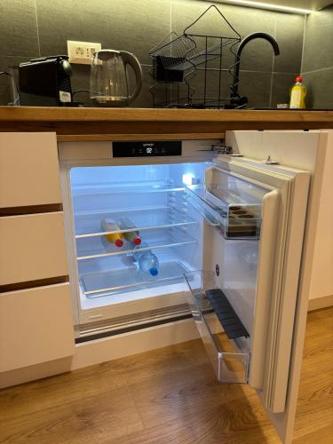 an empty refrigerator with its door open in a kitchen at Apartment Aqua Serena in Palić