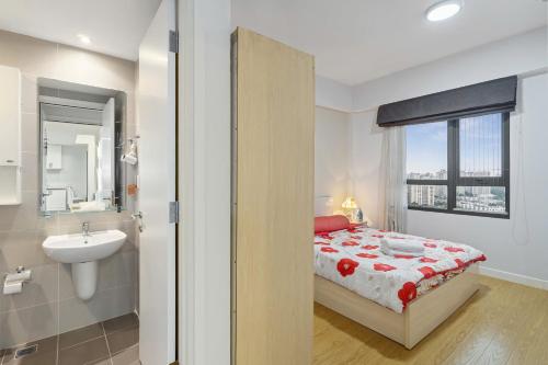 a bedroom with a bed and a sink and a window at Masteri Thao Dien Riverside Apartment in Ho Chi Minh City