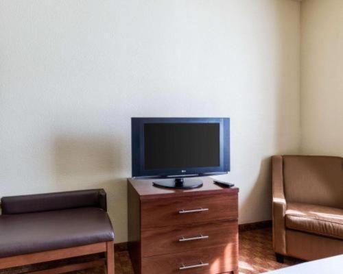 a living room with a tv on a wooden dresser at Comfort Suites near NASA - Clear Lake in Webster
